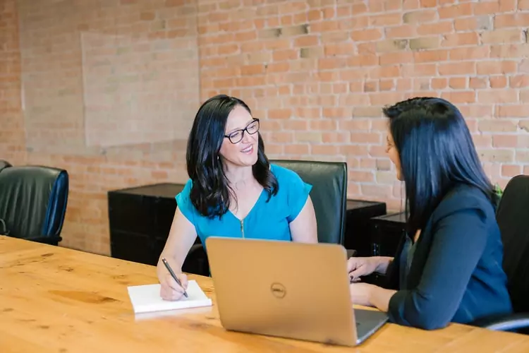 two women at a conference table smiling and talking