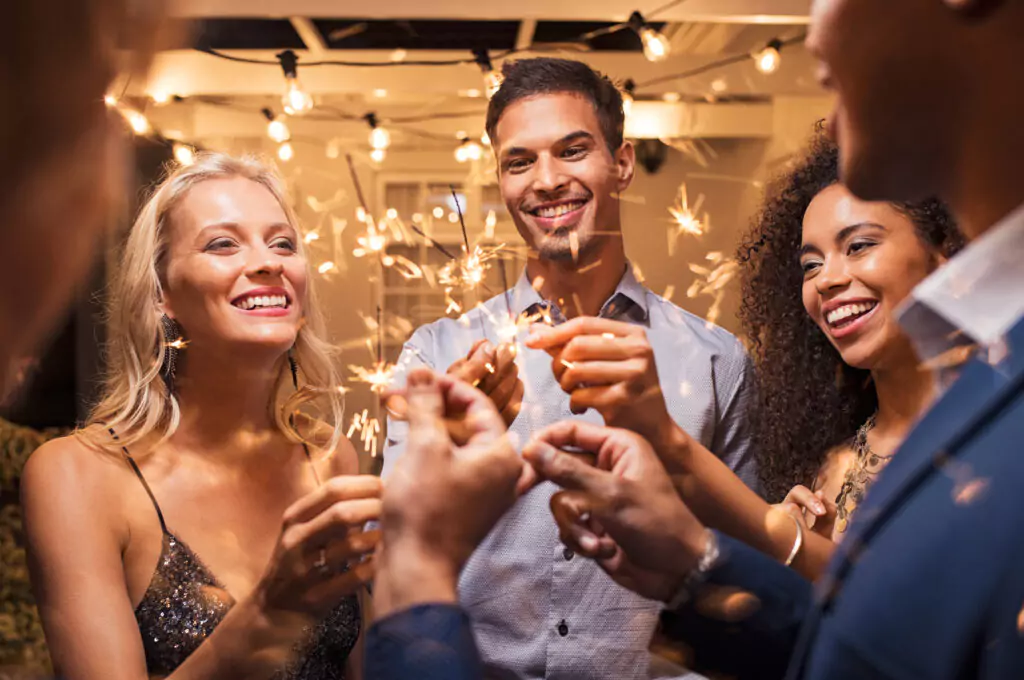 a group of people smiling and holding sparklers