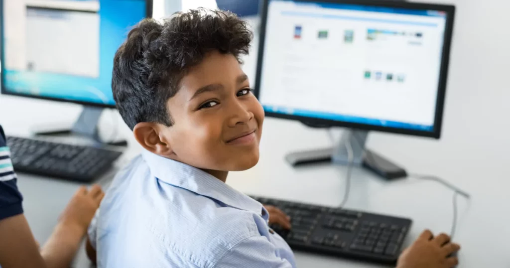 boy using a computer smiling at camera