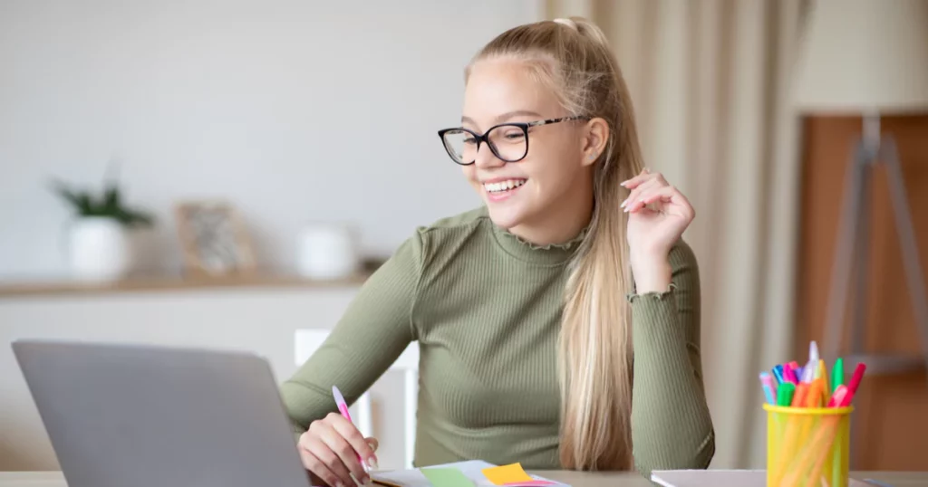 girl in green smiling at laptop