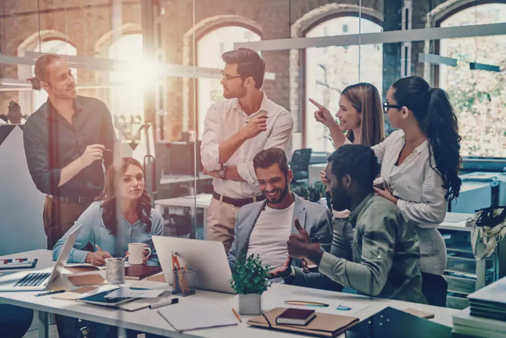 a group of happy people in an office talking and laughing