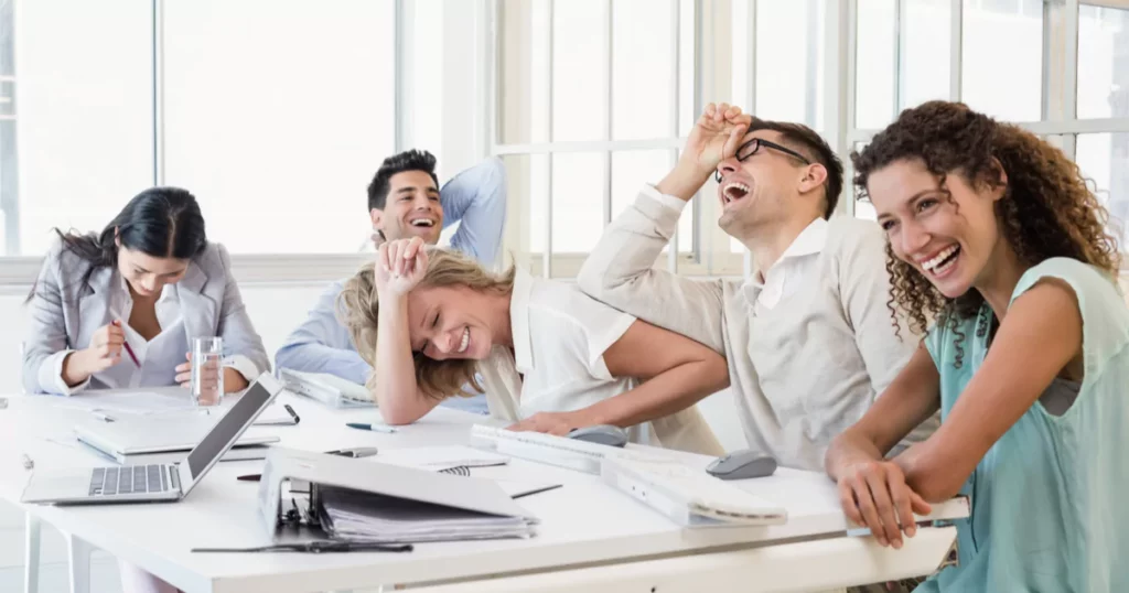 Corporate colleagues laughing in an office at a big table