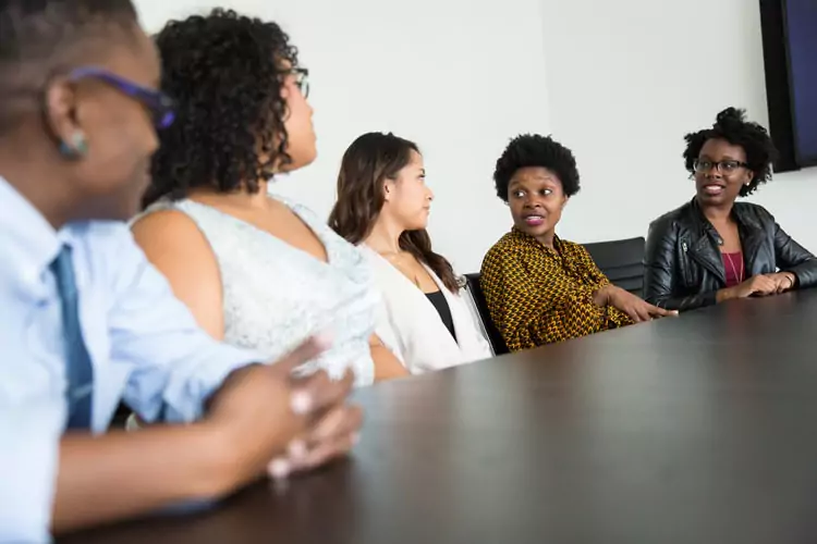 colleagues listening to a woman speak at a table together