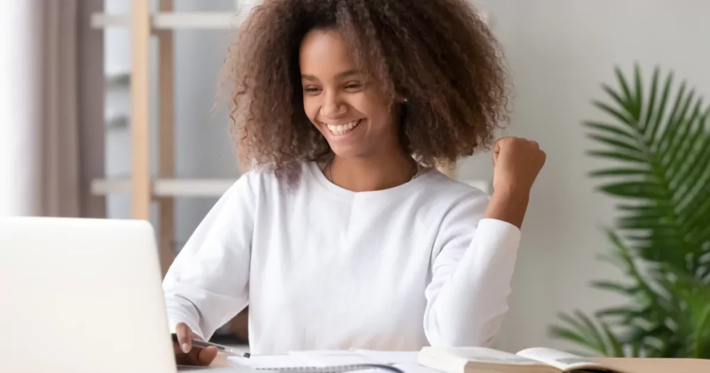 smiling teen girl with curly hair using a laptop