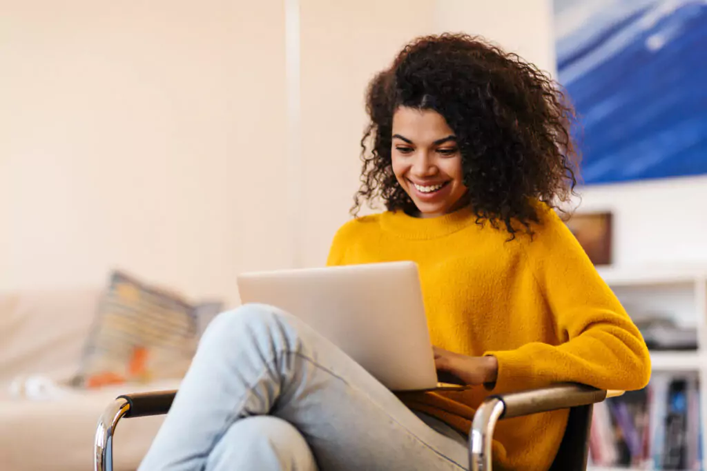 woman in orange sweater using a laptop