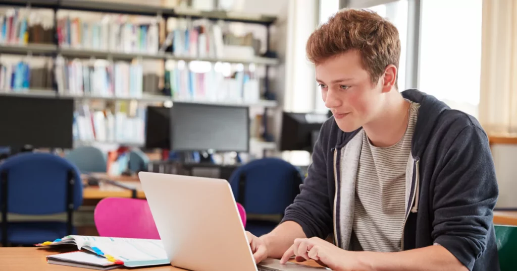 teen boy in hoodie using a laptop