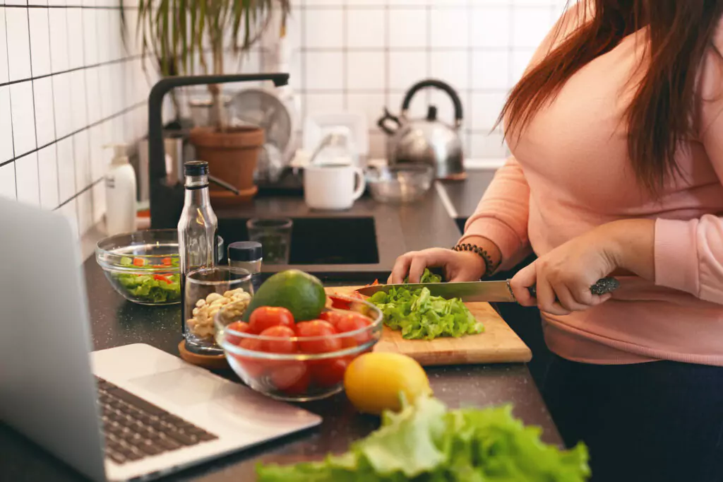 woman cooking in a kitchen with a laptop