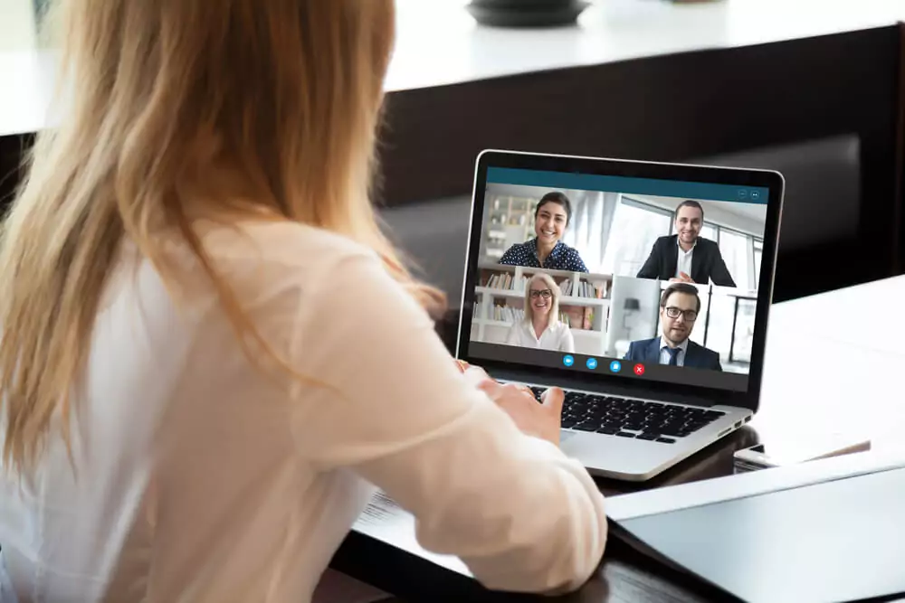 a woman on a teleconference meeting on a laptop with smiling people