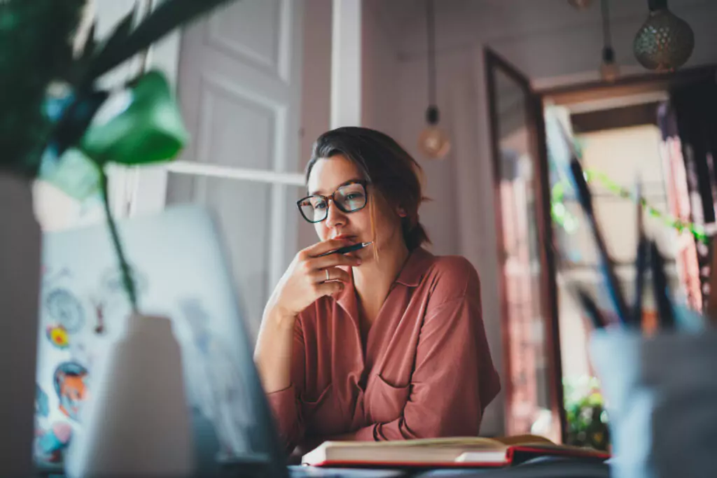 woman with a pen using a laptop