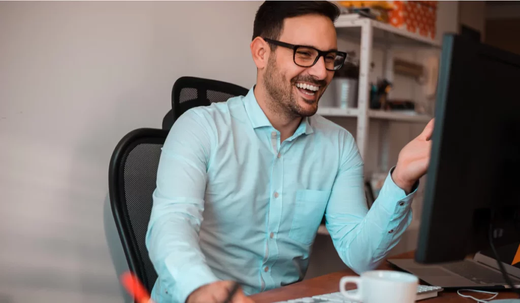 laughing man in button up on computer