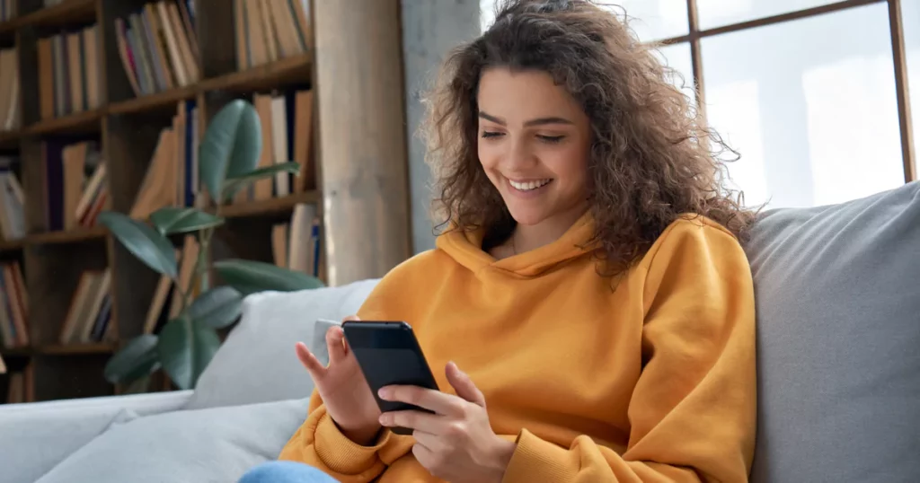 woman in orange hoodie on a phone