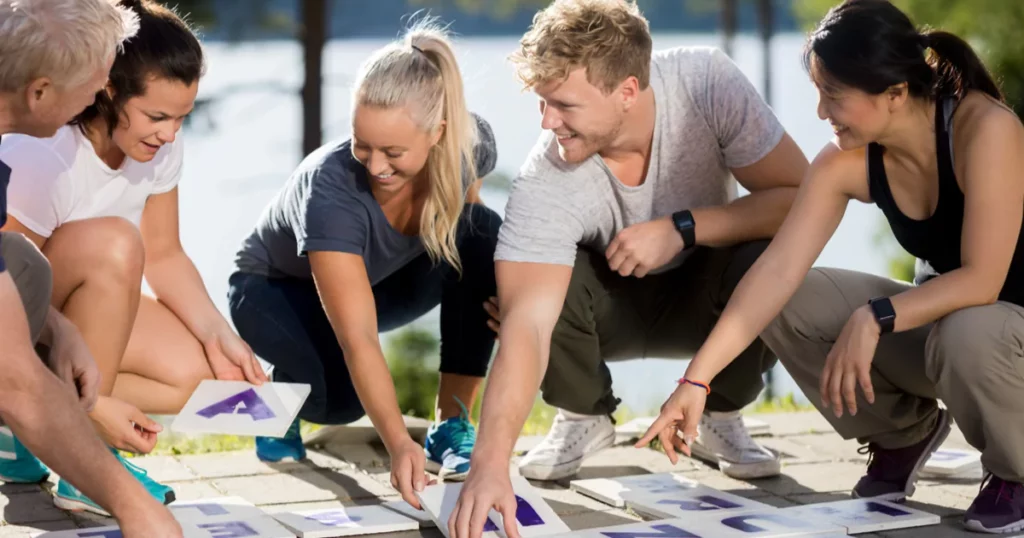 a group of people playing a team building game kneeling over game pieces