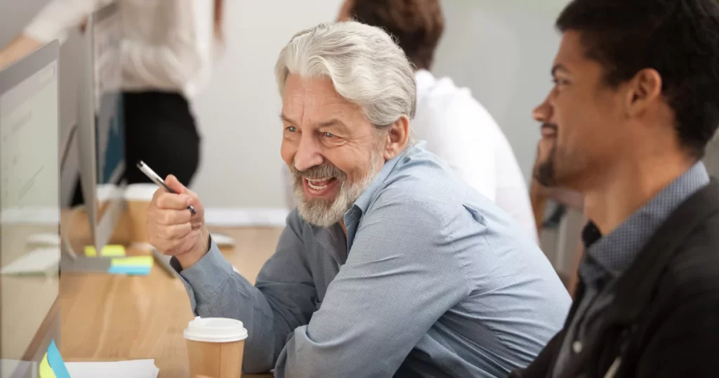 elderly-man-and-young-man-coworkers-desk