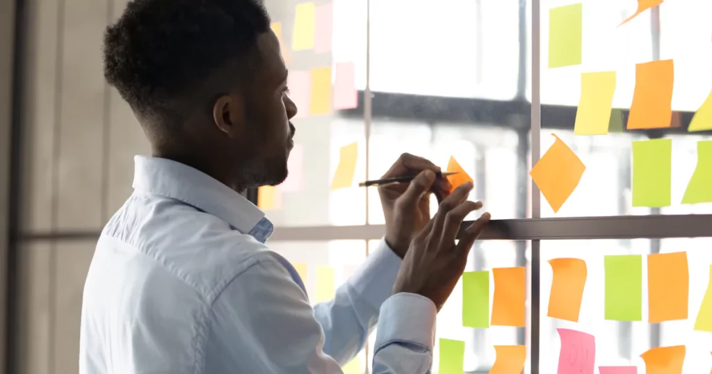 employee writing on post-its on wall