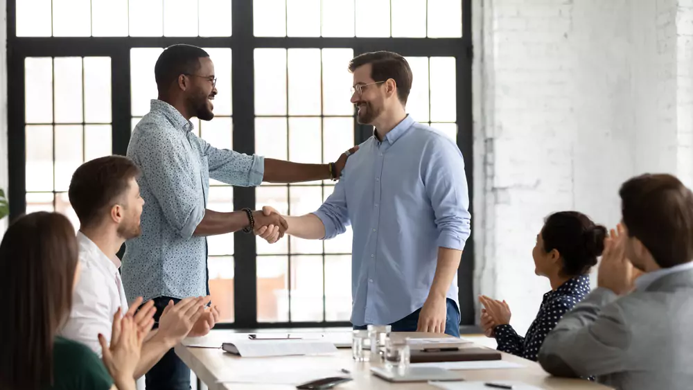 boss congratulating employee in front of others