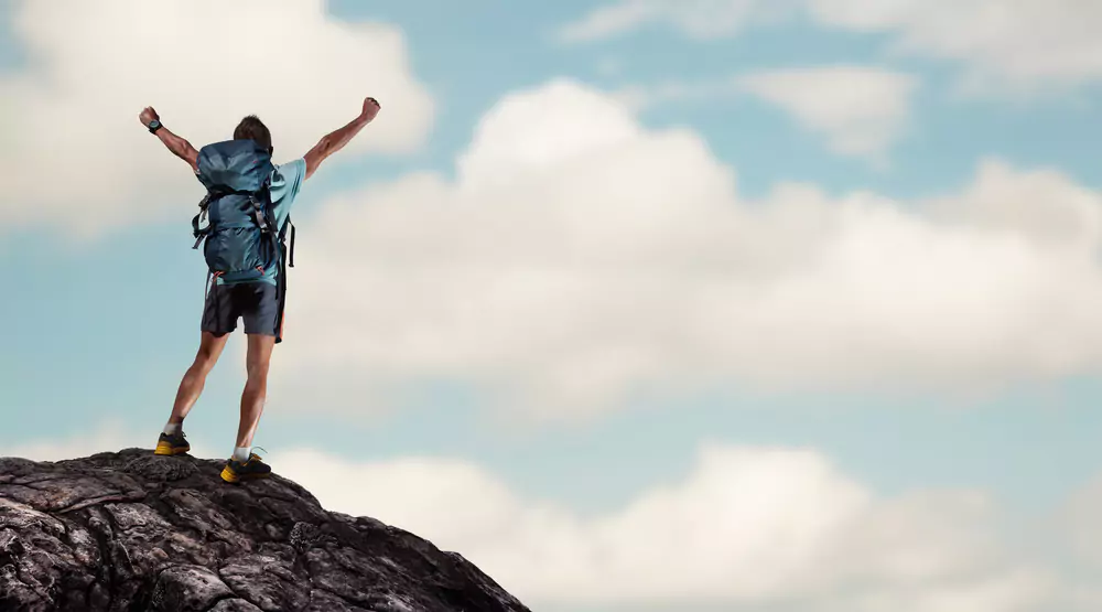 hiker celebrating on top of a mountain