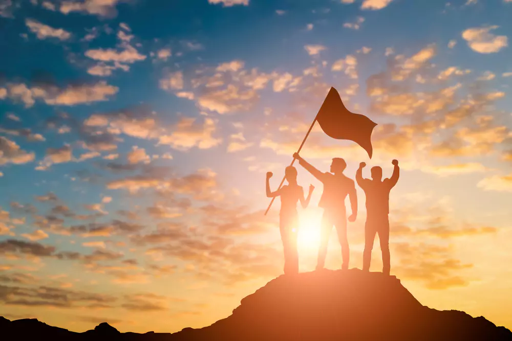 silhouette of team on top of a mountain